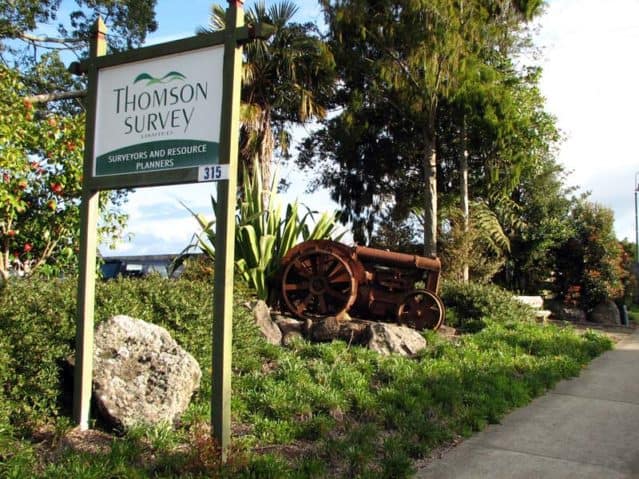 photo of the front garden at the Thomson Survey office on Kerikeri Road, displaying the company sign and a rusty tractor